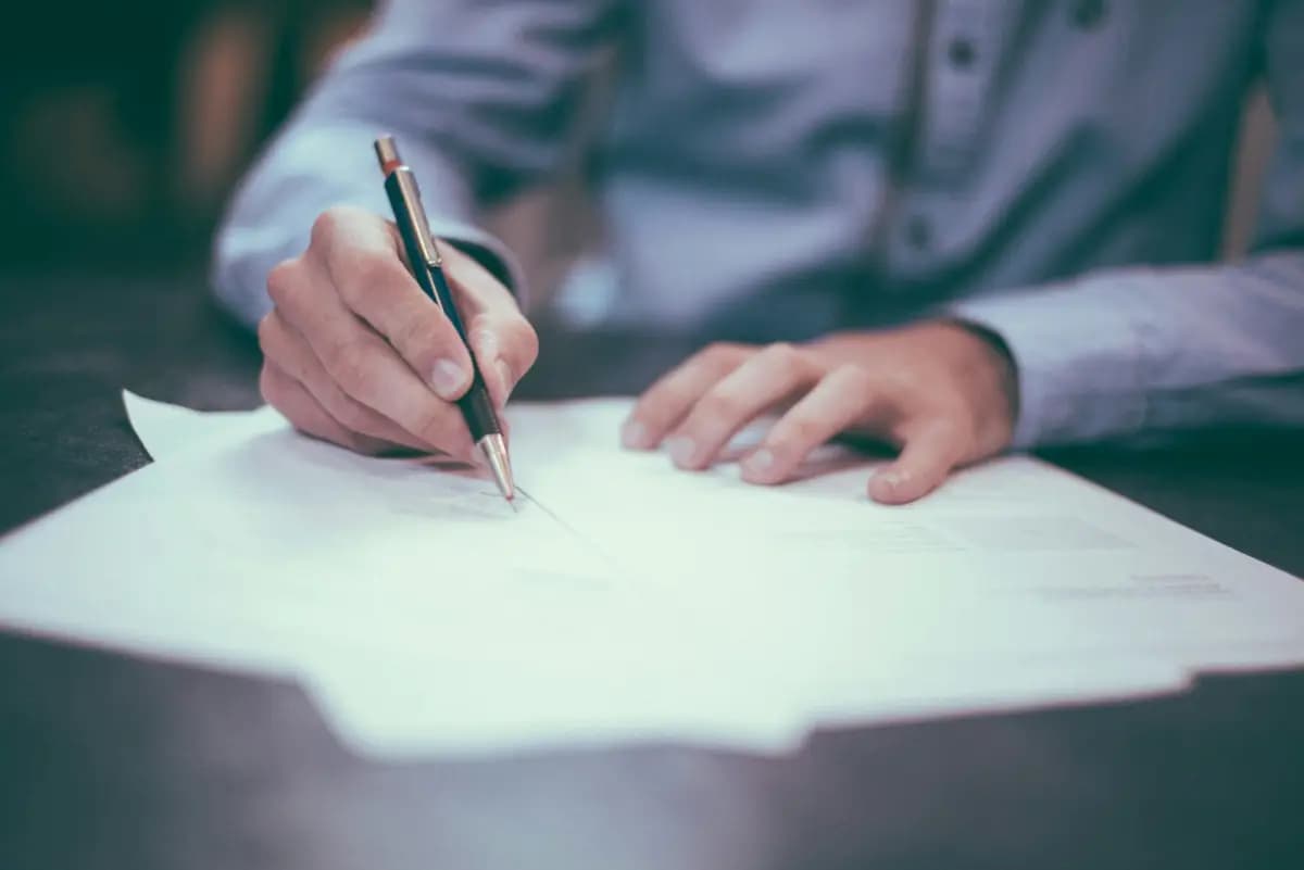 Two hands drafting a document on a sheet